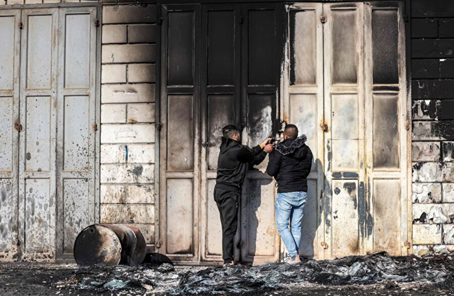 Erkekler bugün Hawara kasabasında yanan bir binanın kapısına kilit vuruyor.