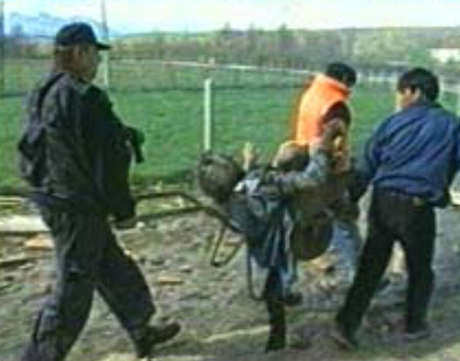 Gjakova Katliamı'ndan yaralı kurtulan bir adam el arabasıyla götürülürken.