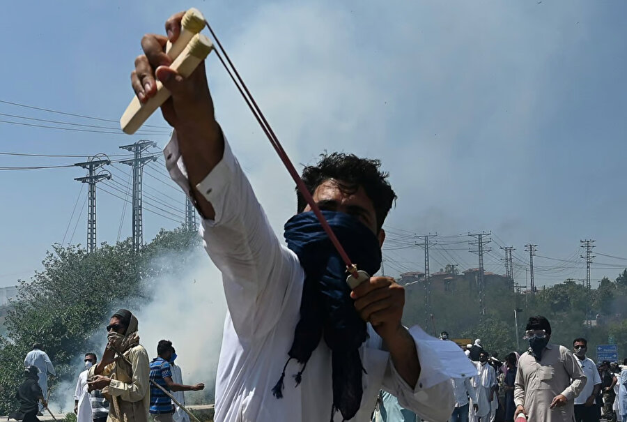Pakistan PTI partisi aktivisti ve eski Pakistan Başbakanı İmran Han'ın destekçisi, liderlerinin tutuklanmasına karşı düzenlenen bir protesto sırasında polise taş atmak için sapan kullanıyor.