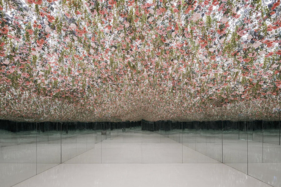 “Düşen Çiçek Bahçesi”, ayna kaplı bir mekanda tavana asılı çiçeklerden oluşuyor ve sonsuz bir çiçek bahçesi görseli oluşturuyor.