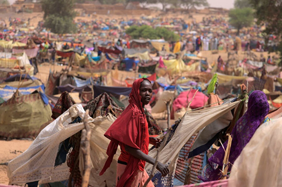 Sudan'ın Darfur bölgesindeki çatışmalardan kaçan ve daha önce Sudan'da ülke içinde yerinden edilmiş Sudanlı genç kız, Sudan sınırına yakın Çad'ın Borota kentine sığınırken derme çatma barınakların yanından geçiyor.