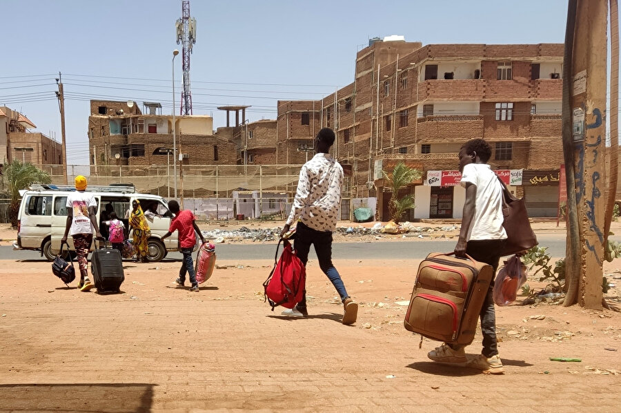 Güney Hartum'u tahliye eden Sudanlılar, minibüslerle şehirden uzaklaşmak istiyor, 14 Mayıs 2023. Sudan'daki çatışmanın patlak vermesinden bir ay sonra, başkent, terörize edilmiş aileler evlerinde toplanıp gıda ve temel ihtiyaç malzemelerinin çaresizce yokluğuna dayanmak zorunda kalan, elektrik kesintilerine, nakit kıtlığına, yüksek enflasyona maruz kalan ve dışarıdaki tozlu, ıssız sokaklarda silahlı çatışmalar şiddetlendiği tehlikeye bir savaş alanına dönüştü.