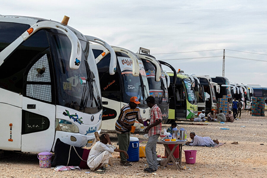 Bir aydır mesaileri bitmeyen Sudanlı sürücüler, Sudan'dan tahliye edilen vatandaşları Mısır'a taşıdıktan sonra, Aswan yakınlarındaki Vadi Karkar köyünde otobüslerinin yanında dinlenirken...
