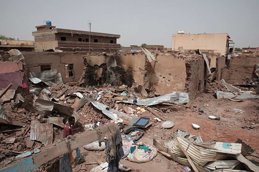 Hartum kentinde son çatışmalarda yıkılan bir evin önünden geçen bir adam.