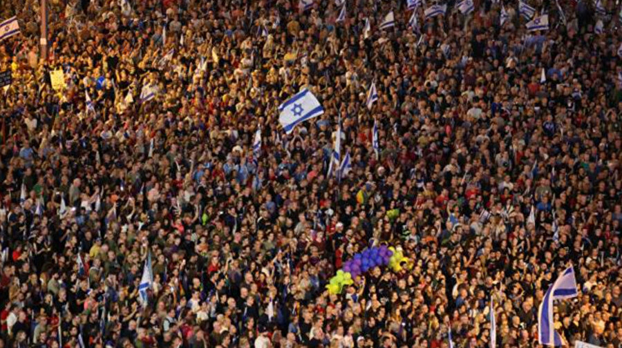 Göstericiler, 3 Haziran 2023'te Tel Aviv'de İsrail hükümetinin yargı revizyonu tasarısını protesto eden bir miting sırasında Mısır sınırı yakınlarında açılan ateş sonucu öldürülen üç İsrail askeri için bir dakikalık saygı duruşunda bulunuyor. 
