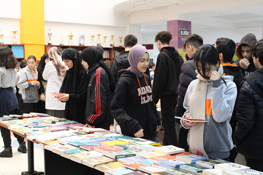 Okula adımımızı attığımızda genişçe bir salonda çok sayıda kitabın yer aldığı kütüphaneler ve hemen önlerinde öğrencilerin sanatsal ve eğitsel eserlerinin bulunduğu sergi alanı vardı.