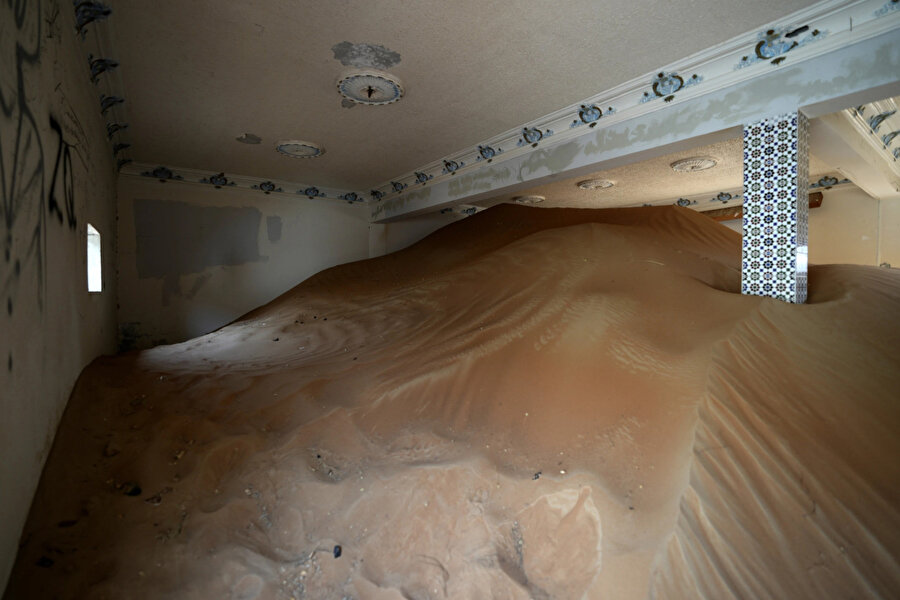 Evlerin içine üflenen kum birikintileri bazı odalarda duvarları kapatıyor ve neredeyse tavana ulaşıyor. 