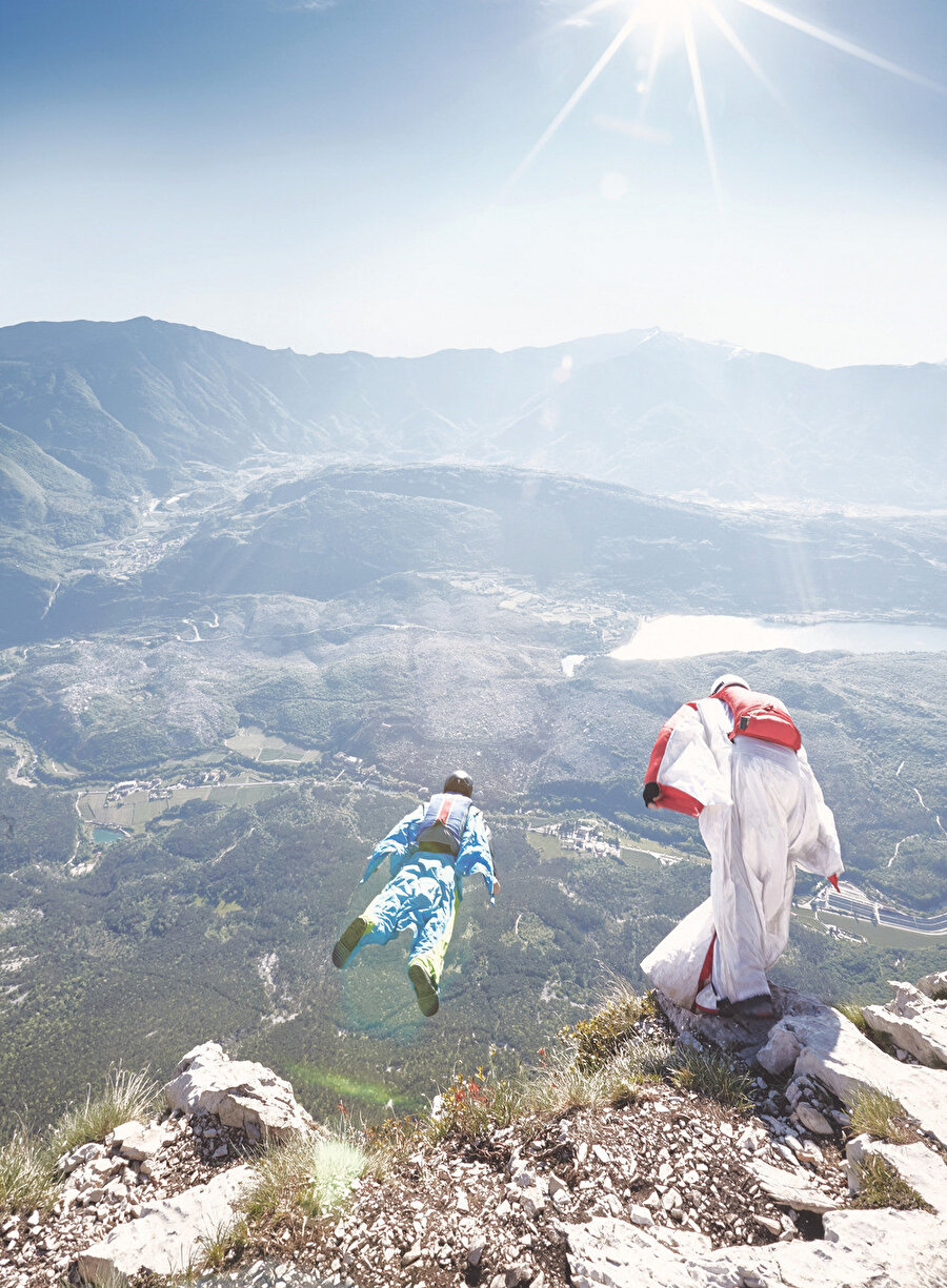 Sporcular, özel kıyafetlerinin yanında yanlarına aldıkları paraşütlerini iniş esnasında açıyorlar.