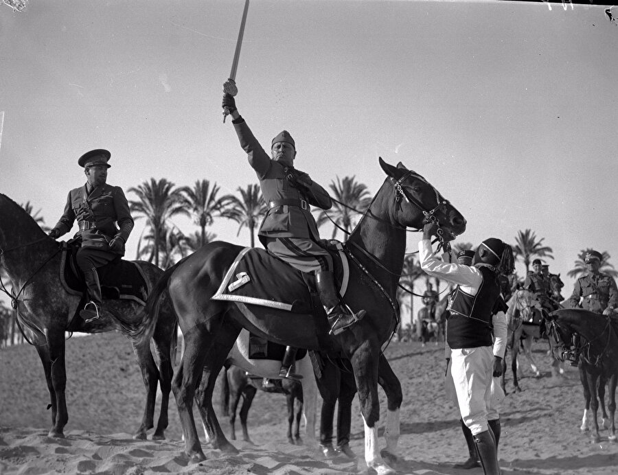 İtalyan Faşist lider Benito Mussolini, Libya'da kendisine takdim edilen "İslâm'ın kılıcı" ile poz verirken, 1937.