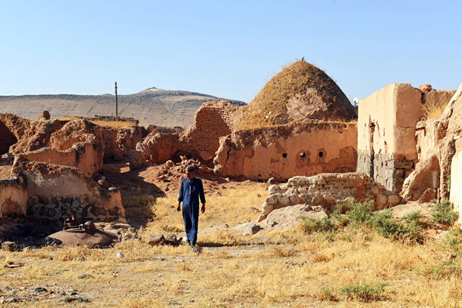 Çatılarında yabani otların yetiştiği terk edilmiş evlerin yanında duran Mahmud el-Mheilej.