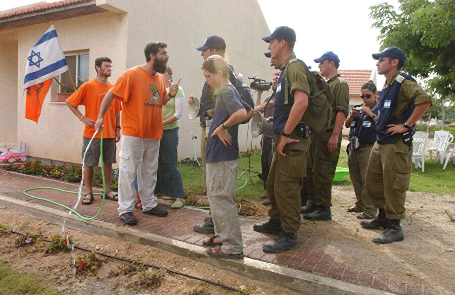Kapı kapı dolaşarak yerleşimcilerin bölgeyi terk etmesi yönünde talimat veren İsrail askerleri.
