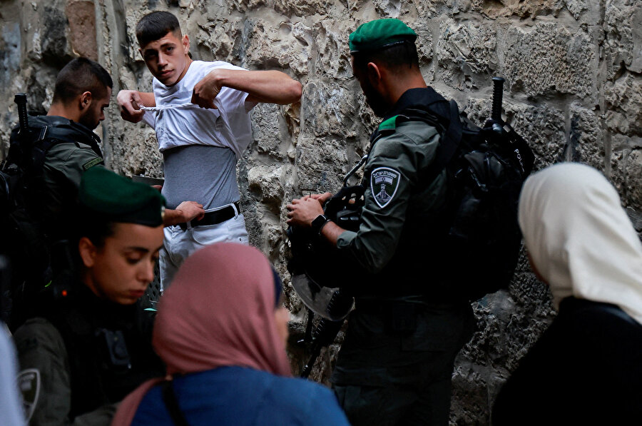 İsrail polisi, 2 Ekim 2023'te Kudüs'ün Eski Şehir bölgesinde, Yahudilerin Sukot bayramı sırasında ibadet edenler rahiplerin kutsamasına katılırken Filistinli bir adamı arıyor.