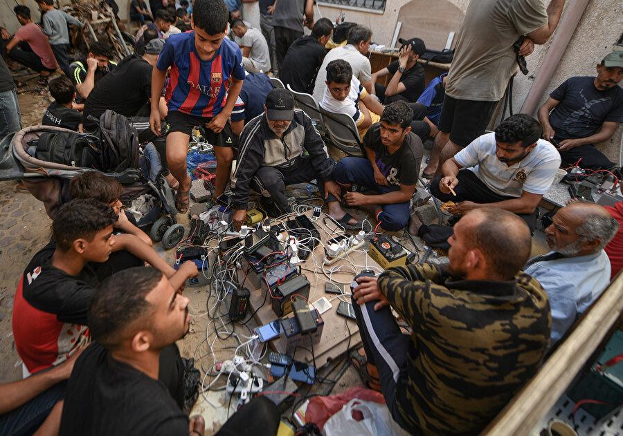 İsrail saldırıları altındaki Gazze'de günlerdir elektrik sıkıntısı yaşanıyor. Filistinliler telefonlarını arabaların aküsünü kullanarak şarj ediyor.