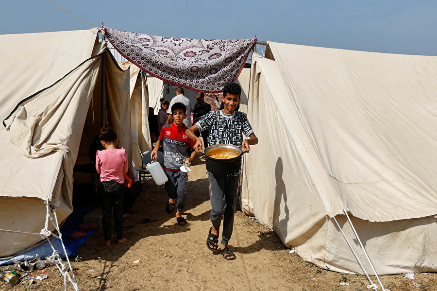 Han Yunus'ta Birleşmiş Milletler tarafından işletilen bir merkezdeki çadır kampında “bir tencere yemekleri olmasının heyecanını yaşayan bir çocuk.”
