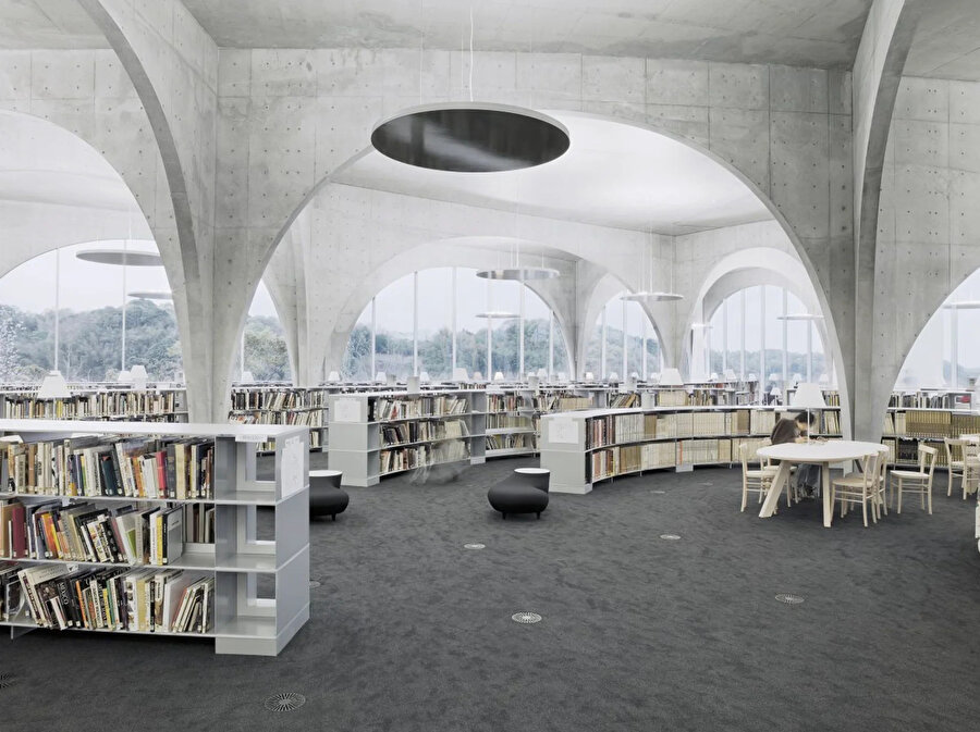 Tama Sanat Üniversitesi Kütüphanesi iç tasarımında kullanılan raflar, kitaplıklar, cam seperasyon üniteleri, brüt beton görünümü yapıya bütünlük, görsellik ve devamlılık katıyor. 