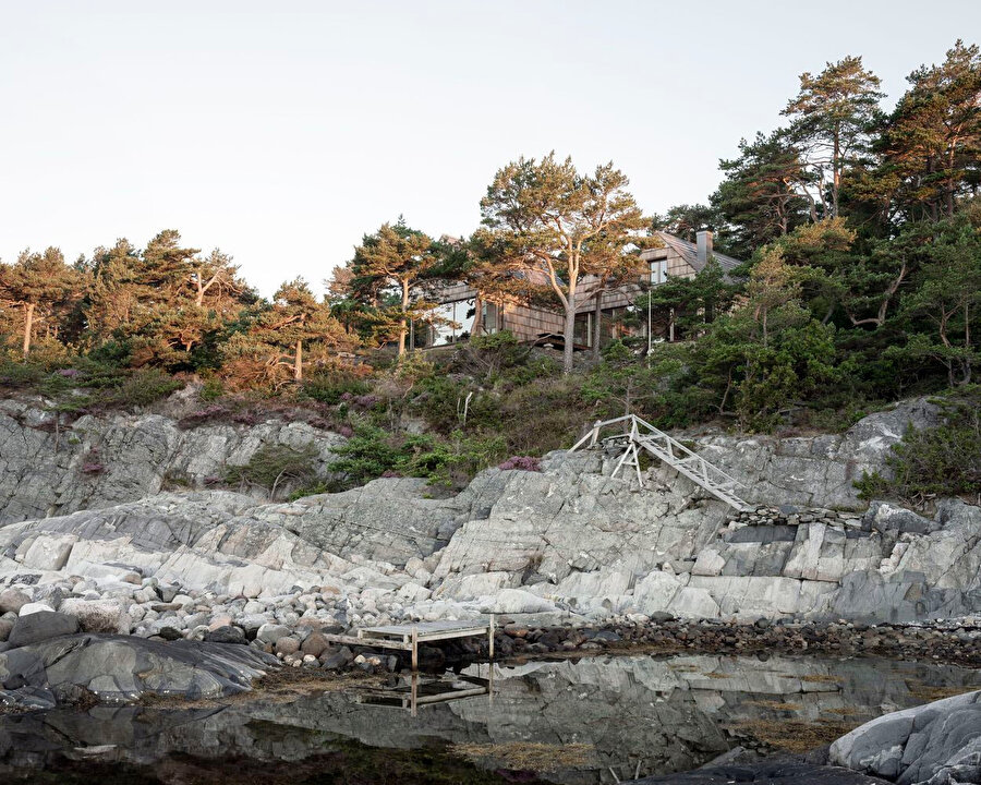 Kayalık kaplı bir sahil şeridinin doğal peyzajı içerisinde saklanıyor. 