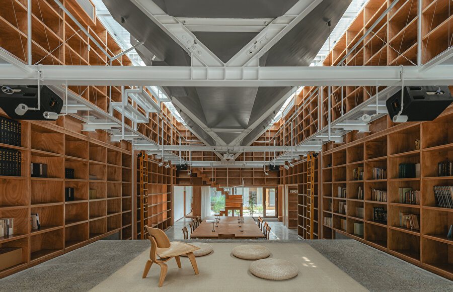 Yapının iç mekanına ait, kitaplıklarla çevrelenmiş çalışma alanı.