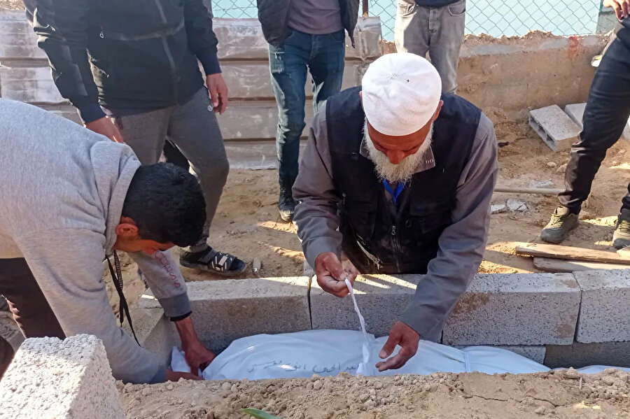 Ebu Cevad, Han Yunus'ta İsrailli bir keskin nişancı tarafından vurularak öldürülen 14 yaşındaki bir çocuğun cesedini gömerken.