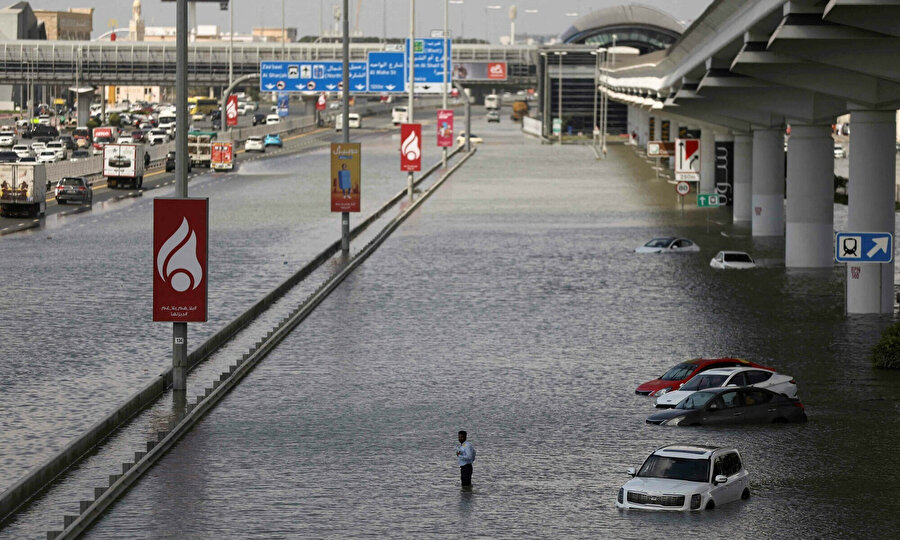 Ortadoğu'nun finans merkezi Dubai'de, şiddetli yağışların ardından sular altında kalan caddede ilerleyen arabalar.