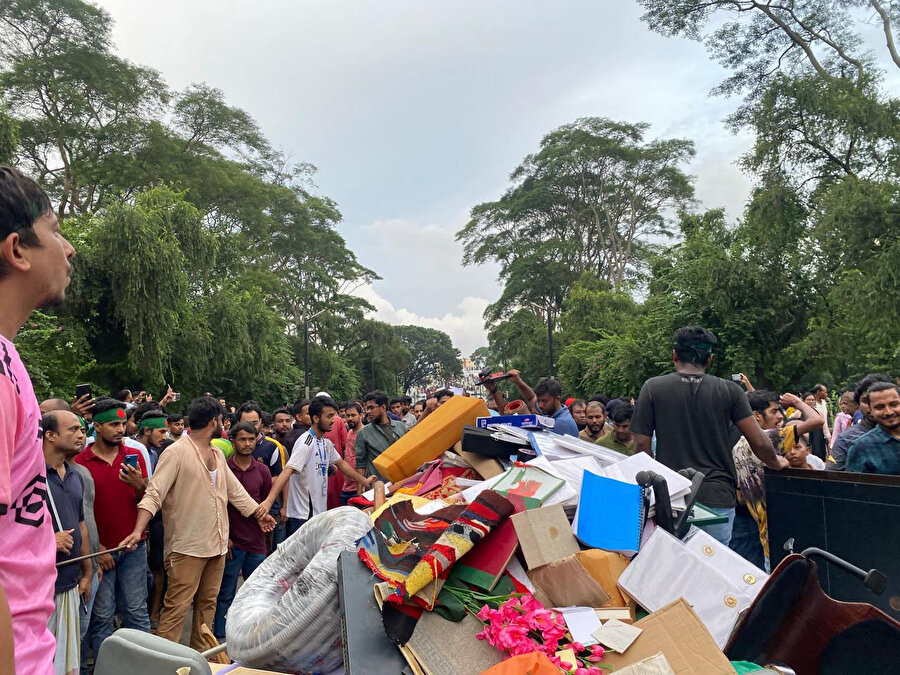Başbakan Şeyh Hasina'nın resmî konutunu basan göstericilerin içerideki eşyaları dışarı çıkardıkları görüldü.