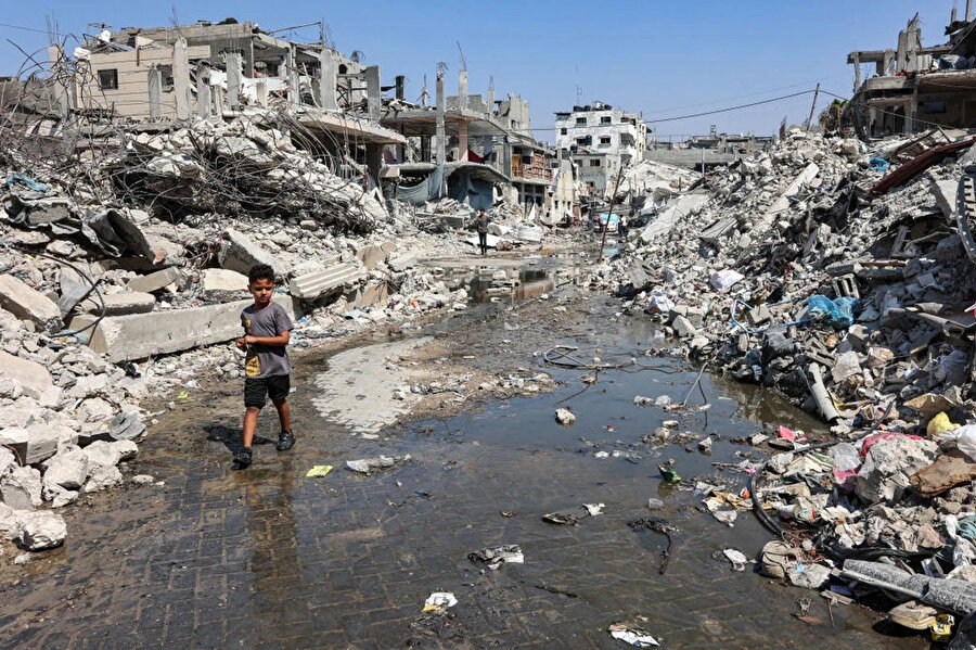 Bombalanan Cibaliye Mülteci Kampı’ndaki kanalizasyon suyu birikintisinde yürüyen Filistinli bir çocuk, 14 Ağustos 2024.