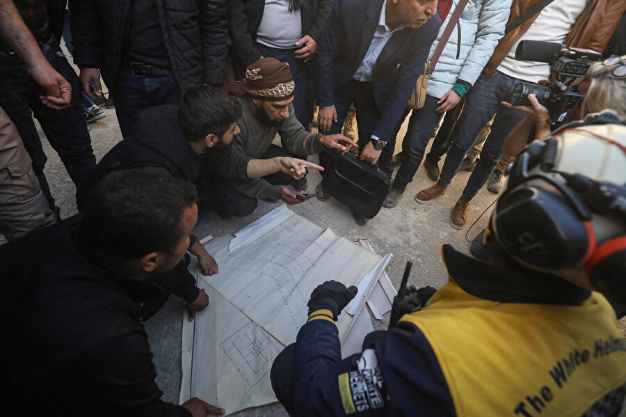 Hapishane çizimlerini inceleyerek gizli bölmeleri bulmaya çalışan yardım ekipleri.