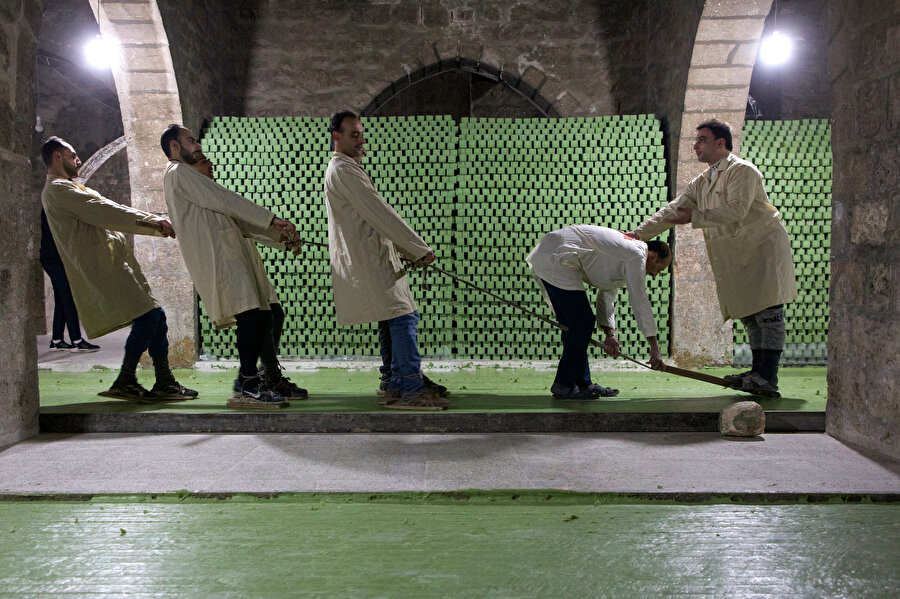 Soğutulmuş sabunu kesmek için bir kişinin bıçak yüklü tabağın üzerinde durması ve dört kişinin onu ve bıçakları katı sabunun içinden çekmesi gerekiyor.