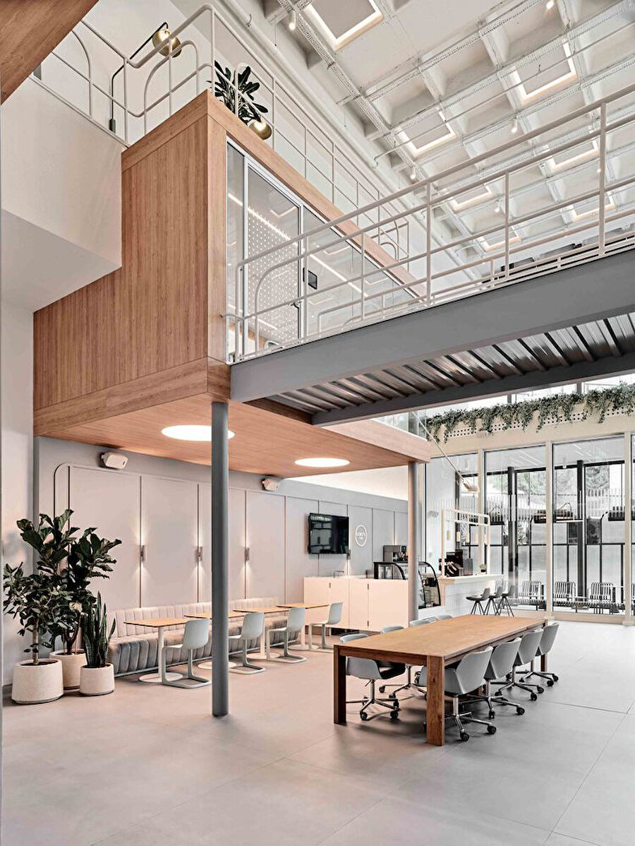 Çift katlı mekan organizasyonu, ahşap detaylar ve minimalist mobilyalarla iş ve dinlenme alanlarını bir araya getiriyor. 