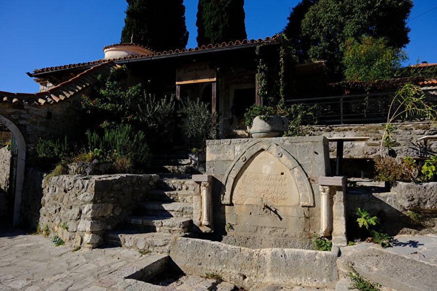 Ömerbaşı Camii’nin önünde yer alan çeşme, ardında Çardak ve tekke, solda caminin girişi.