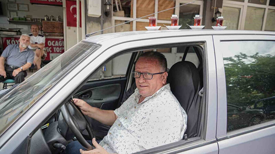 50 metre uzaklıktaki çay ocağından aldığı çayları otomobiliyle taşıyor