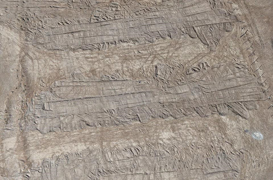 Zümer kasabası yakınlarındaki çölde bulunan toplu mezarı örten toprakta buldozer izlerinin yukardan çekilmiş görüntüsü, 27 Şubat 2025.