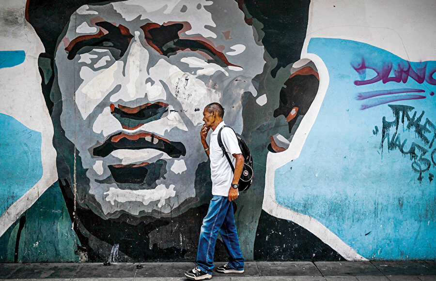 Evet, Maduro haklıydı. Aynı senaryo yine sahnedeydi çünkü. Trump, tıpkı oğul Bush’un Chavez’e yaptığı gibi Caracas sokaklarını ülkedeki yerel ajanları marifetiyle birbirine kattı. Yaptırımlar ve ekonomik operasyonlar marifetiyle ülkede müthiş bir enflasyon hüküm sürüyordu. Dünyanın bilinen en büyük petrol rezervine sahip olan Venezuela yokluk içinde kıvranıyordu.