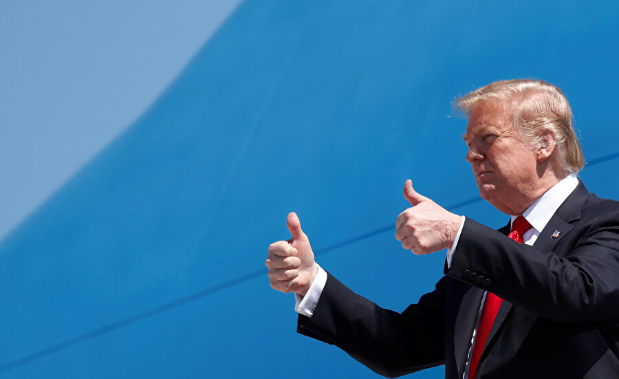 ABD Başkanı Donald Trump uçaktan inerken basın mensuplarına poz veriyor.