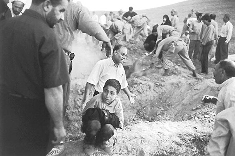 2002 Eric Grigorian
İran'da asker ve köylüler, depremde ölen kurbanlar için mezar kazıyorlar. Bir çocuk ise ölen babasının pantolonuna sıkı sıkı sarılmış, yanıbaşındaki boşluğa babasının gömülmesini bekliyor.