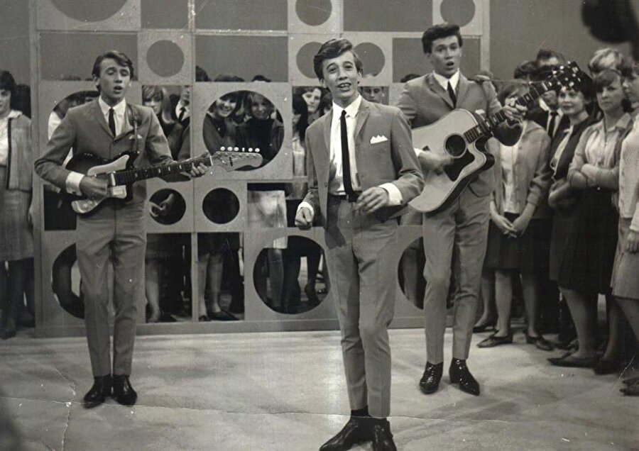 
                                    
                                    
                                    
                                    
                                    
                                    Grup 1963 yılında grubun baş harfleri olan “B” ve “G” harflerinin üzerinde oynayarak isimlerini Bee Gees olarak değiştirdi.
                                
                                
                                
                                
                                
                                