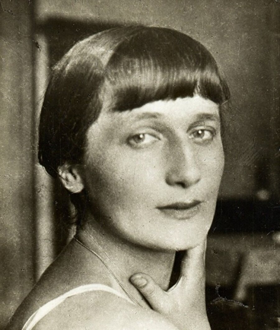 Anna Ahmatova
Akhmatova, Stalin'in Sovyet Rusya'sında yaşamış bir kadın şairidir. Şiirlerindeki erotik, mistik üslubu ve politik aldırmazlığı yüzünden Sovyet rejimi tarafından reddedildi ve yaklaşık 20 yıl şiirleri tutsak kaldı. . Mükemmel bir lirik şairi olan Akhmatova'nın adına yazılmış şiir ve sayısız resim vardır. Akhmatova, her zaman hüzünlüdür ve şiirleri yoğun biçimde hüzün içerir.
Aynı bardaktan su içmeyeceğiz!
Aynı bardaktan içmeyeceğiz,
Ne suyu, ne tatlı şarabı,
Şafakta öpüşemeyeceğiz
Ve akşam çöktüğünde pencereden bakmayacağız.
Sen güneşle soluklanıyorsun ben ay ile
Ama aynı aşkla yanıyoruz ikimiz de.
Benim yanımda sadık, sevgili yarim,
Senin yanında neşeli eşin,
Ama okuyorum gri gözlerindedi korkuyu
Çünkü sensin acım.
O arada bir buluşmalarımız bundan böyle
Daha bir arada bir olsun.
Gönlümüz rahat olsun, o zavallı gönlümüz.
Şiirlerimde yalnız senin sesin var
Senin şiirlerinde, biliyorum benim soluğum esiyor
Ah bir ateş ki cesareti yok
Ne unutuşa, ne korkuya dokunmaya…
Bir bilsen nasıl seviyorum şu an
O kuru dudaklarını, gül rengi!