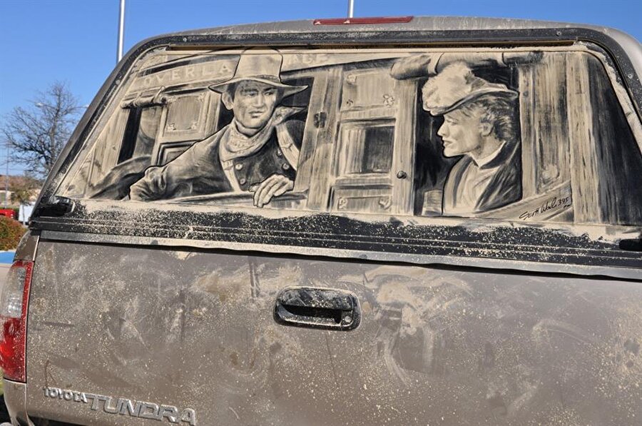 O, resimlerini, kirli ve toz içindeki araba camlarının üzerine çiziyor.

                                    
                                