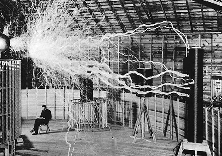 Nikola Tesla büyütücü verisi ile laboratuvarında otururken
