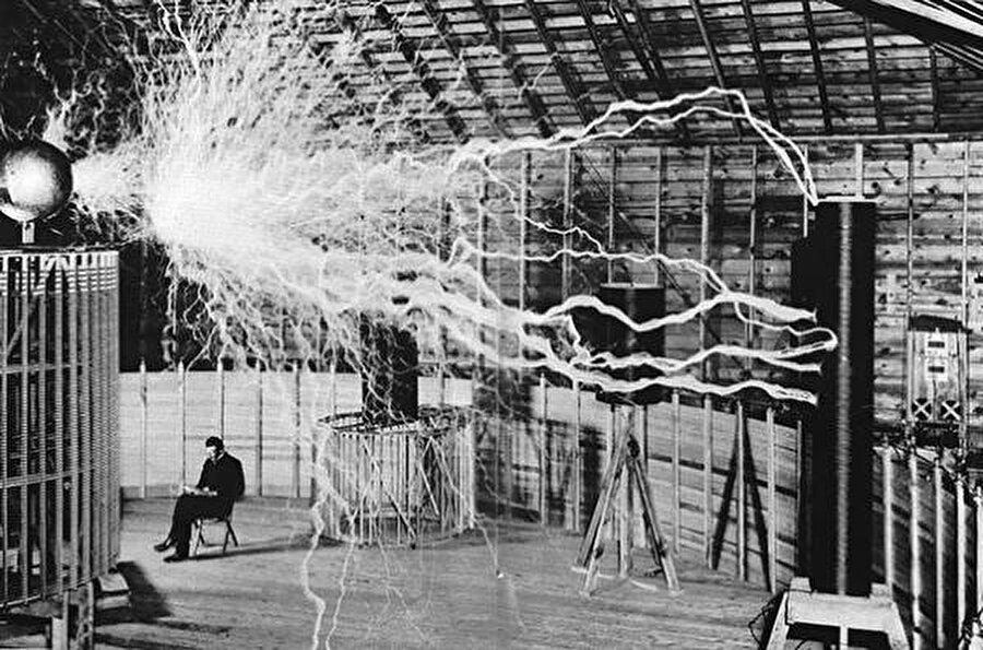 
                                    Ünlü mucit Nikola Tesla, kablosuz güç vericinin arkasında oturuyor
                                