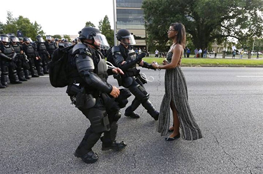 Leshia Evans: Polis vahşetini zarifçe protesto etmek
Bir çok kişi adını bilmese de Leshia Evans'ın, Temmuz ayında Baton Rouge-Luisiana'da gerçekleşen Black Lives Matter eylemi sırasında simgesel bir fotoğrafı çekildi. Protesto, Baton Rouge polisinin silahsız Afro-Amerikalı olan Alton Sterling'i öldürmesi sonrasında gerçekleşmişti. Evans, polis ablukasının önünde zarif ve sakin bir şekilde durdu ve polis üzerine geldikçe hareket etmeyi reddetti. Fotoğraf çekildikten kısa bir süre sonra da gözaltına alındı.
