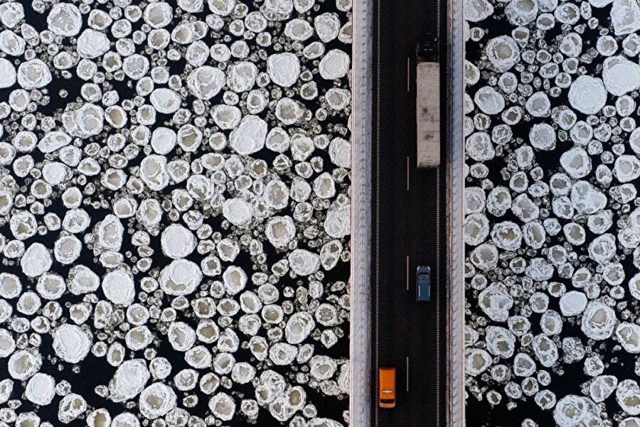 Donmuş bir nehrin üzerindeki köprüde seyahat eden taşıtlar

