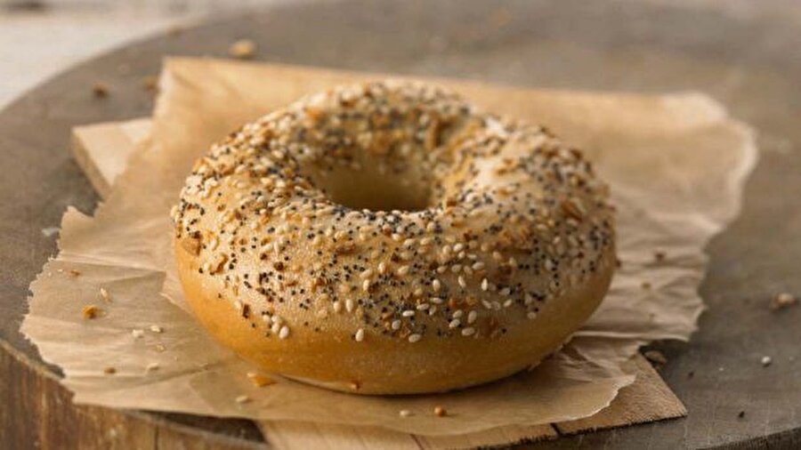Bagel + Amerika
Bagel, ABD, Kanada ve Birleşik Krallık'ta yaygın olarak tüketilen mayalı hamurdan yapılmış kalın ve halka şeklinde bir ekmek çeşididir.İlk kez Polonya'da ortaya çıktığı varsayılan Bagel'ın yapımında maya, un, şeker, tuz ve su kullanılır. Şekil bakımından açmaya benzer, tat bakımından ise susamsız simiti andırır. İlk zamanlar Yahudi azınlıklar tarafından tüketilen Bagel, daha sonra ABD ve Kanada'da yaygınlaşmıştır. Amerika'da özellikle New York ve Kaliforniya eyaletlerinde çok tüketilmektedir. Simitten farklı olarak suda haşlanan bagel ın susamlı, çörekotlu, sarmısaklı, soğanlı, haşhaşlı çeşitleri vardır. Genellikle ortadan kesilip ısıtılarak, içine krem peynir, domates, salam konularak kahvaltıda yenilebildiği gibi, İngiltere'de içine biftek, tavuk veya ton balığı konularak sandviç olarak yenilmektedir.