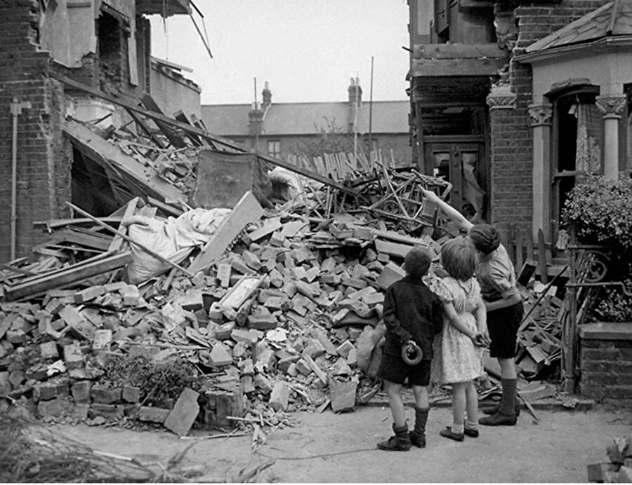 II. Dünya Savaşı sırasında Alman uçakları tarafından evi bombalanan bir çocuk harabelerin arasından kendi odasını gösteriyor
