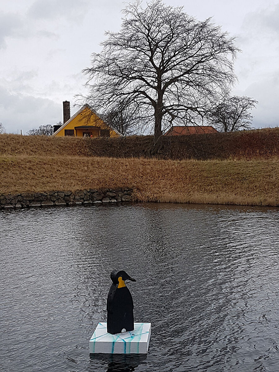 Sanatçı buz parçasının üzerinde duran penguen maketlerini Landskrona şehir merkezindeki kanaldan suya bıraktı.