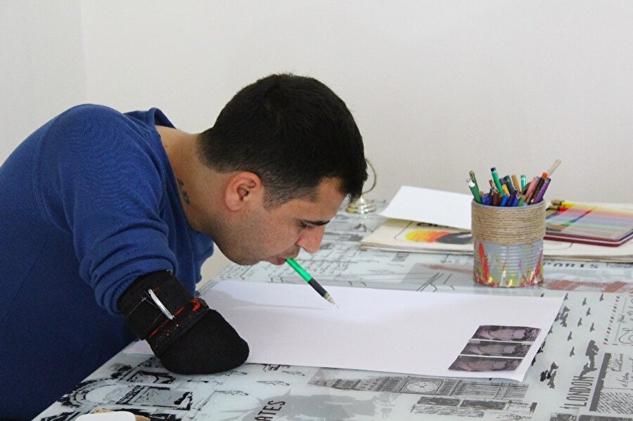 Yusuf Akgün, dişleriyle çizim yapıyor. 