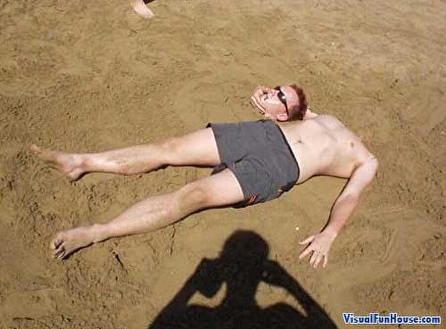 Голова ноги туловище. Мужчина лежит на песке.