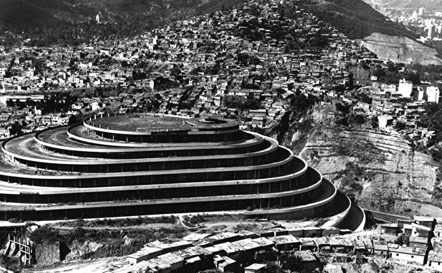 
                                    
                                    
                                    Eğimli
bir piramit şeklinde olan bu cesur yapı, sarmal gibi yükselen zeminler üzerinde
yükseliyor. Ancak bugün Venezuela'nın çoğunda olduğu gibi bina da farklı
bir hikayeler anlatıyor.
                                
                                
                                