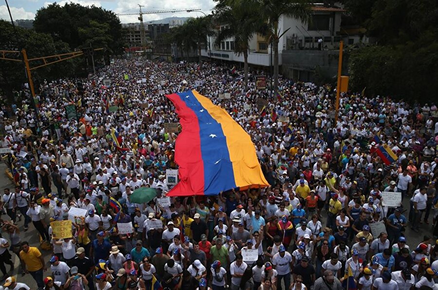 Protesto gösterileri başladı, onlarca kişi öldü

                                    
                                    Aylardır devam eden gıda sıkıntısı ve hiperenflasyon beraberinde şiddet ve yağmalama olaylarını getirdi. ABD ile Avrupa ülkelerinin desteğinin alan muhalefetin seçim kazanmasının ardından Maduro daha sıkı politikalar izlemeye başladı. Hükümet, bazı muhalefet liderlerini ABD ile birlikte rejim değişikliği yapmak için ülkeyi karıştırmakla suçlarken, protesto gösterileri artarak devam etti. Protestoların birinci ayında 1 Mayıs’ta Başkan Maduro "barışın yeniden tahsisinin tek yolu" olduğunu söyleyerek, yeni anayasanın yazılmasına karar verdiğini açıkladı. Bu muhalefetin düzenlediği protestoları daha da alevlendirdi.Bu zamana kadar süren protestolarda 100'den fazla kişinin yaşamını yitirdiği bildirildi.
                                
                                