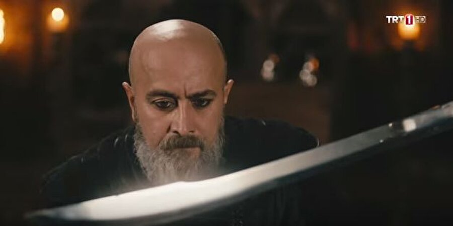 İşte o sahne!
Dizinin son bölümünde Ertuğrul Bey, Emir Sadettin Köpek'i ormanda pusuya düşürerek öldürüyor. Fakat tarihi kaynaklar Sadettin Köpek'i öldürenin Ertuğrul olmadığını söylüyor. Tarihi kaynaklara göre, Emir Sadettin Köpek'in ölümü Kubadabad Sarayı'nda gerçekleşiyor. Tarihi kaynaklara göre Emir Sadettin Köpek'in ölümü şu şekilde: Saltanat naibliği ve pervanecilik görevlerine getirilen Sadeddin Köpek, gücünü kanıtlamak için Melikü'l Ümera ünvanıyla sefere çıkmıştır ve 1238 yılında Eyyubiler'in denetiminde bulundurdğu Samsat Kalesi ve diğer bazı kaleleri ele geçirmiştir. Anadolu Selçuklu tahtına geçmek isteyen Köpek, tahtta hak iddia edebilmek adına I. Gıyaseddin Keyhüsrev'in annesi Şehnaz Hatun ile gayri meşru ilişkisi olduğu ve annesinin iki aylık hamileyken bir başkasıyla evlendiğini, kendisinin de bu evlilikten yedi ay sonra dünyaya geldiğini yani I. Gıyaseddin'in gayri meşru çocuğu olduğu yönünde iddialar ortaya attı. Gözü tahtta olan Köpek, tüm bu iddiaların yanı sıra devletin kötü gidişinden de Sultanı sorumlu tuttu ve Sultanın Abbasi halifelerinin sancağını değiştireceği, Abbasileri tanımayacağı söylentisini yaydı. II. Gıyaseddin Keyhusrev, Köpek'in gücünün artmasından endişelenince 1238 senesinde Köpek ile birlikte Kubadabad Sarayı'na geldi ve Köpek'i bertaraf etmek için güvendiği hassa kölelerinden birini Sivas Subaşısı Hüsameddin Karaca'ya gizlice gönderip Köpek'i ortadan kaldırmasını emretti. Bu emri duyan Hüsameddin Karaca, Kubadabad Sarayı'nda bulunan sultanın yanına gitmeden önce Köpek'e misafir olup güvenini kazanmaya çalıştı ve sultanın hizmetine girmek istediğini kendisine bildirdi. 1239 yılında Hüsameddin Karaca kendisine güvenmeye başlayan Köpek'i bir ziyafet sırasında öldürmeye çalıştı fakat başarılı olamadı. Fakat bu sırada Emir-i Alem Togan'ın kılıç darbesiyle yaralanan Sadeddin Köpek kendini sultanın şaraphanesine attı ve burada şarabdar ve adamları tarafından öldürüldü. Cesedi ise demir bir kafes içine konulup sarayın kale burcuna asıldı.