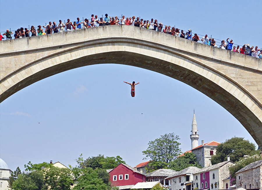 Nehrin soğuk sularında bir gelenek...
2005 yılında Dünya Mirası Listesi’ne eklenen Mostar Köprüsü’nün eğlenceli bir de aktivitesi bulunuyor.


İlk olarak 1664 yılında yapılan ve her sene temmuz ayında gerçekleştirilen bu aktivitede, genç erkekler kendilerini Neretva Nehri’nin sularına bırakıyor. Kulağa ilk başta korkutucu gelse de özgürlüğün zirvesinde hissettiren bu atlayış, onların en büyük eğlence anlayışı... Nehrin buz gibi sularına dalmak, aynı zamanda onların cesaretlerini sergilemek için gerçekleştirdikleri bir gelenek...